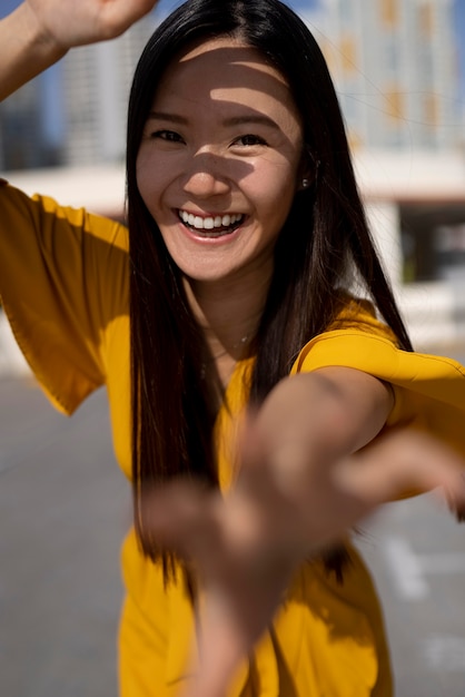 Free Photo portrait of beautiful asian woman in yellow dress posing outdoors in the city