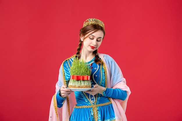 Portrait of beautiful azeri woman in traditional dress with semeni on red