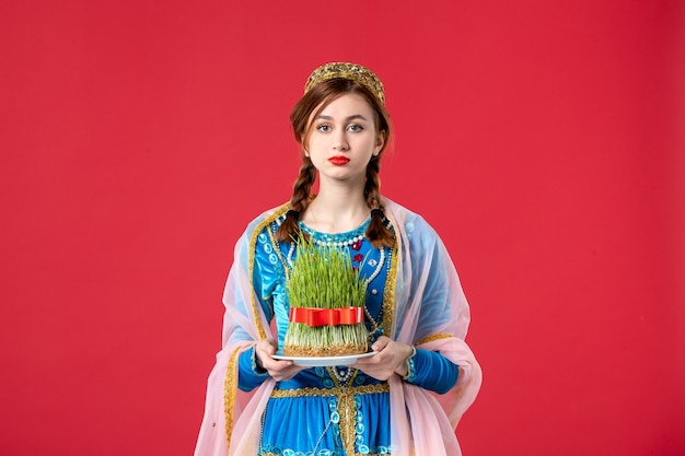 Portrait of beautiful azeri woman in traditional dress with semeni on red