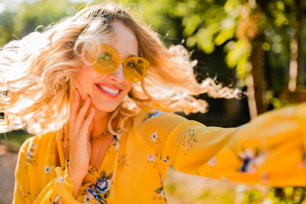 Free Photo portrait of beautiful blond stylish smiling woman in yellow blouse wearing sunglasses making selfie photo