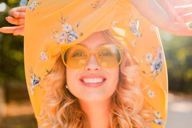 Portrait of beautiful blond stylish smiling woman in yellow blouse wearing sunglasses