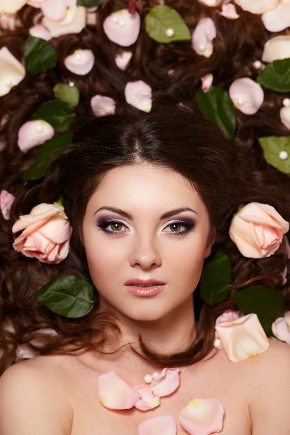 Free Photo portrait of beautiful brunette woman with long curly hair and bright makeup witjh flowers in hair