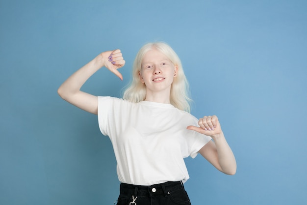 Portrait of beautiful caucasian albino girl isolated on blue  wall