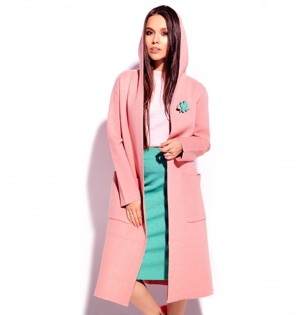 Portrait of beautiful caucasian smiling brunette woman model in bright pink overcoat and summer stylish blue skirt isolated on white background