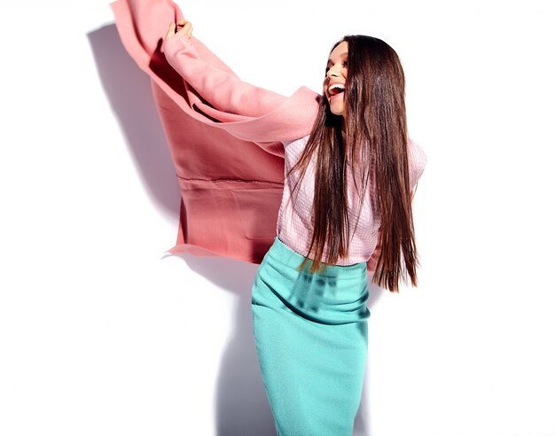 Portrait of beautiful caucasian smiling brunette woman model in bright pink overcoat and summer stylish blue skirt