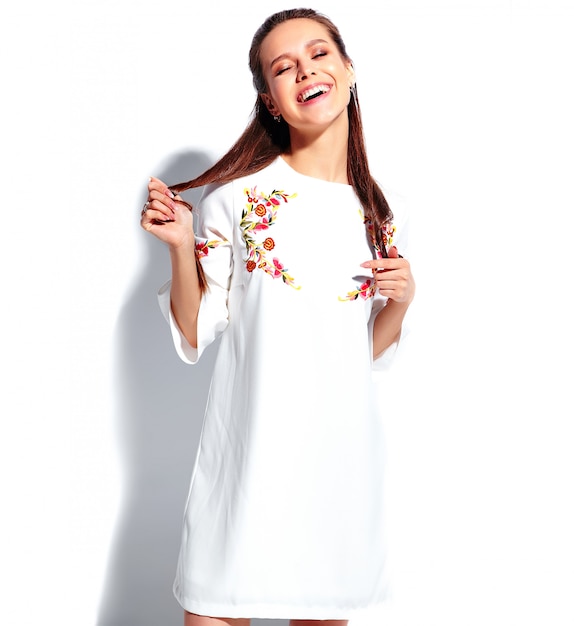 Free Photo portrait of beautiful caucasian smiling brunette woman model in white summer stylish dress isolated on white background. twisting her hair