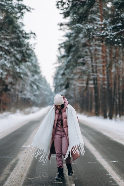 Free photo portrait of a beautiful caucasian woman on a road in snowy forest