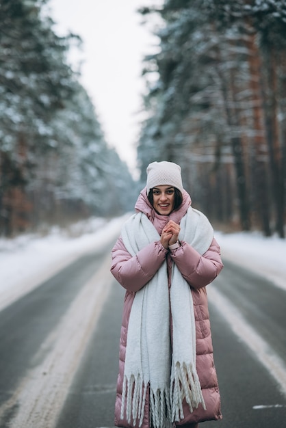 Free photo portrait of a beautiful caucasian woman on a road through snowy forest