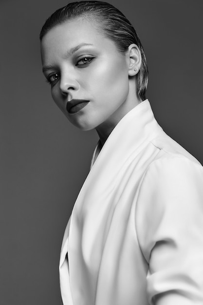 Portrait of beautiful fashion stylish brunette woman model with evening makeup and red lips in white jacket