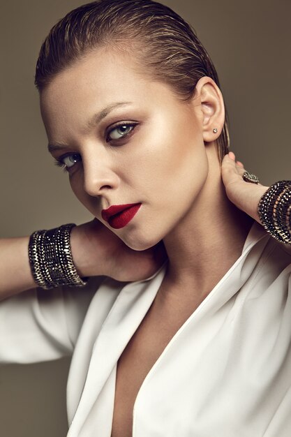 Portrait of beautiful fashion stylish brunette woman model with evening makeup and red lips in white jacket