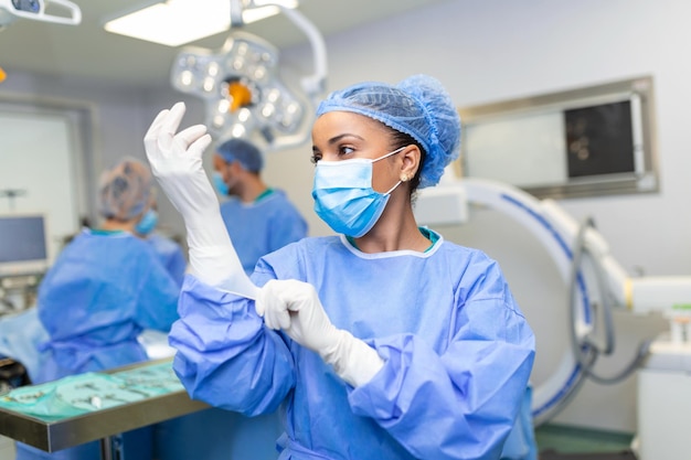 Portrait of beautiful female doctor surgeon putting on medical gloves standing in operation room Surgeon at modern operating room