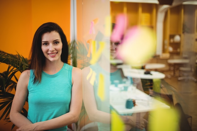 Free photo portrait of beautiful female executive leaning on a glass wall