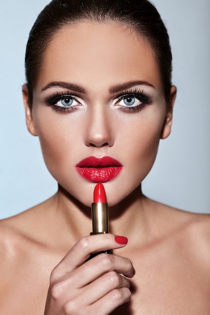 Free photo portrait of beautiful girl model with evening makeup with red pomade in hands