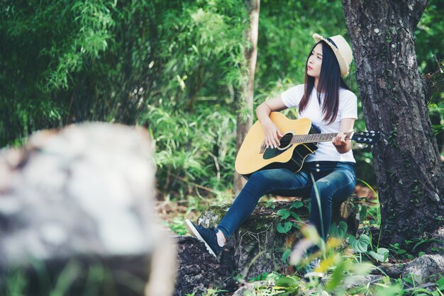 Portrait of beautiful girl playing the guitar with writing at nature