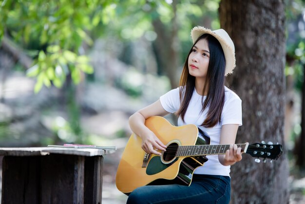 Portrait of beautiful girl playing the guitar with writing at nature