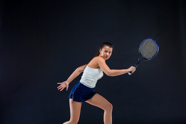 Free photo portrait of beautiful girl tennis player with a racket on dark wall