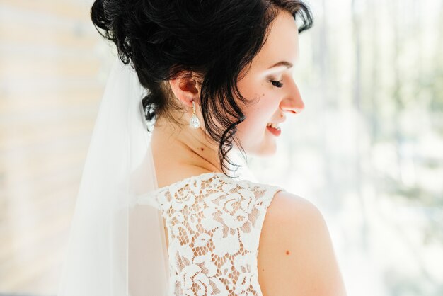 Portrait of a beautiful happy bride in front of a window. Wedding preparations. 