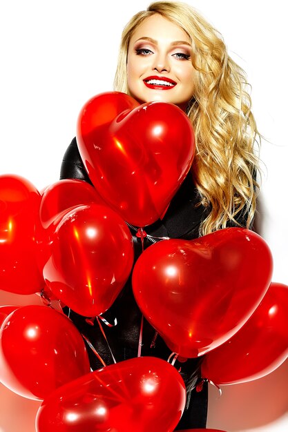 Free photo portrait of beautiful happy sweet smiling blonde woman girl holding in her hands red heart balloons in casual black hipster clothes