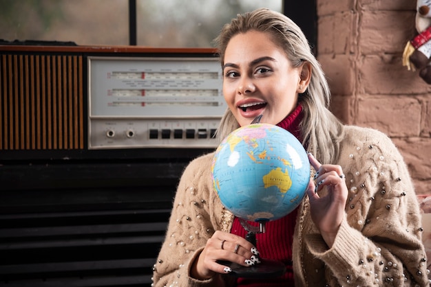 Portrait of beautiful lady pointing at a world globe 