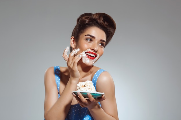 Portrait of beautiful pin-up woman eating cake