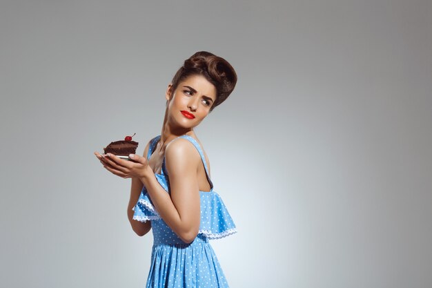 Portrait of beautiful pin-up woman holding cake in hands