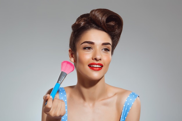 Portrait of beautiful pin-up woman holding make-up brush