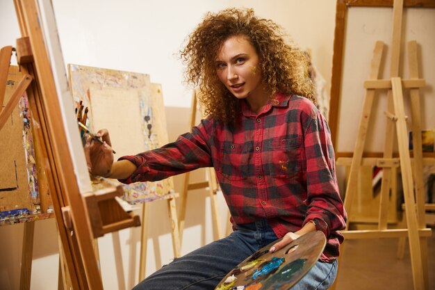 Free photo portrait of beautiful redhead curly artist during her work