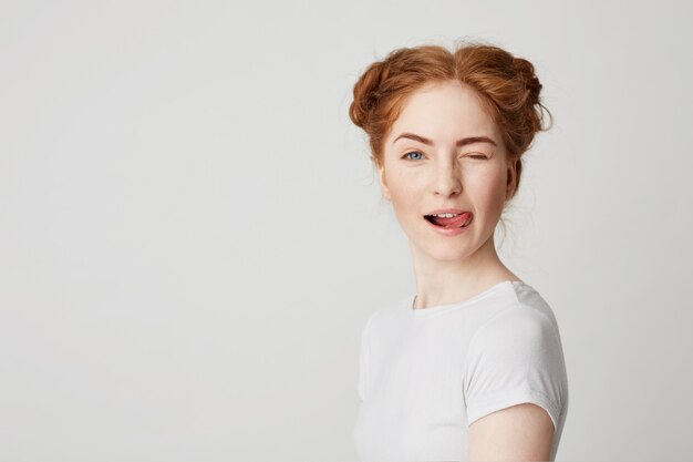 Portrait of beautiful redhead girl smiling showing tongue winking .