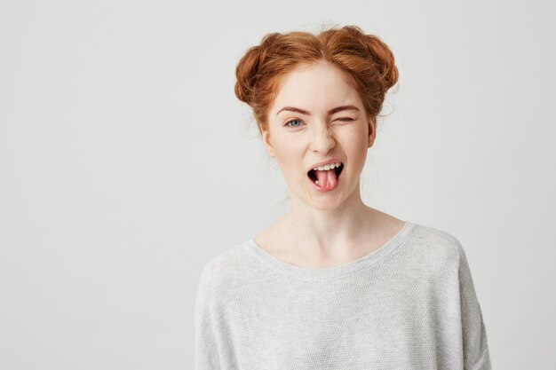 Portrait of beautiful redhead girl smiling showing tongue winking .