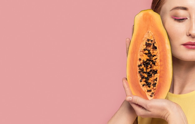 Free Photo portrait of beautiful redhead woman holding a fruit with copy space