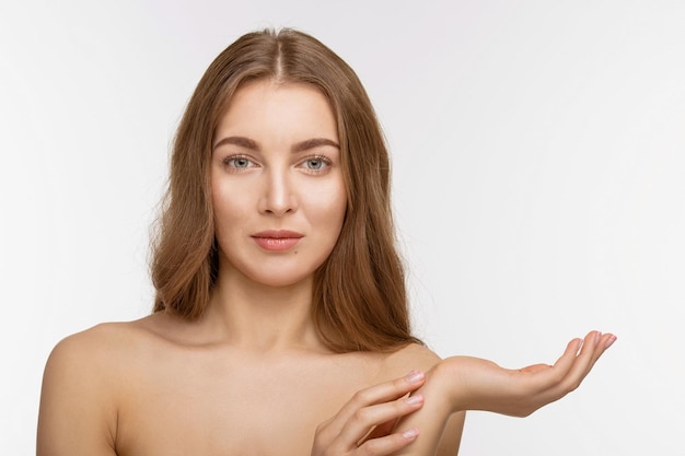 Free photo portrait of beautiful shirtless lady holding hand in front of her over white background. pretty woman with brown hair looking at camera.