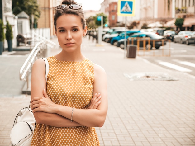 Free Photo portrait of beautiful smiling model dressed in summer yellow dress. trendy girl posing in the street. funny and positive woman having fun