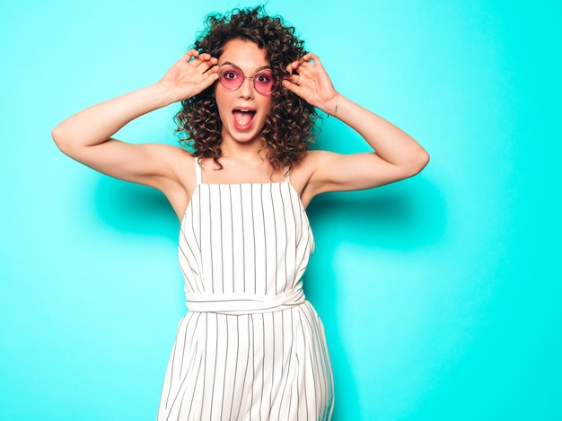 Free photo portrait of beautiful smiling model with afro curls hairstyle dressed in summer hipster clothes.sexy carefree girl posing near blue wall.trendy funny and positive woman