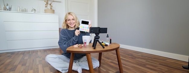 Free Photo portrait of beautiful smiling woman recording video in her room has camera on coffee table reviewing