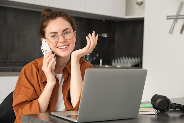 Free photo portrait of beautiful smiling woman working from home talking on mobile phone calling client