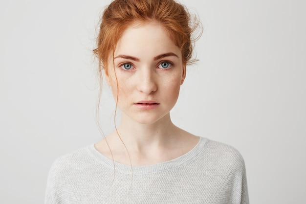 Portrait of beautiful tender ginger girl with blue eyes posing .