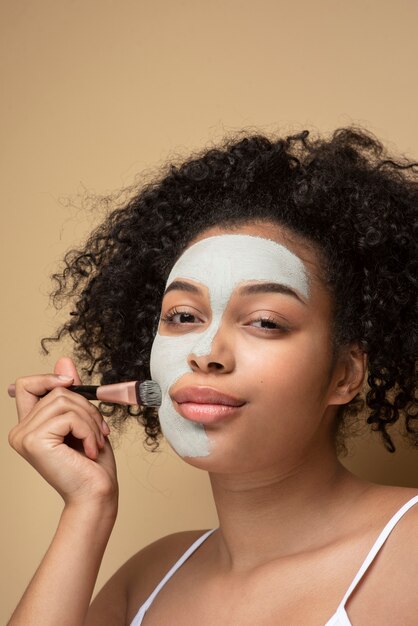 Portrait of a beautiful woman applying face mask with a make-up brush on her face