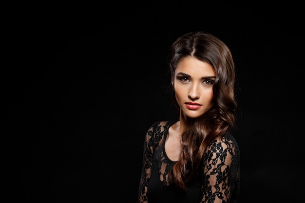 Free photo portrait of beautiful woman in black dress over dark wall