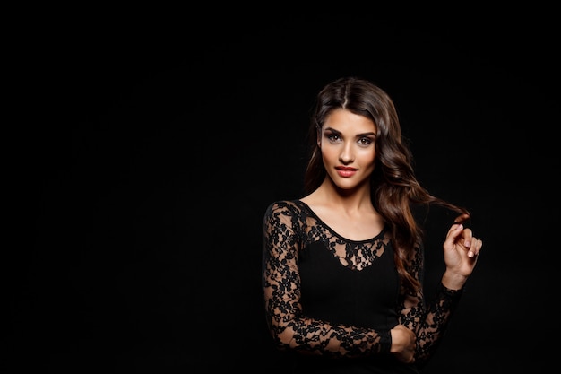 Free photo portrait of beautiful woman in black dress over dark wall