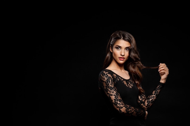 Free photo portrait of beautiful woman in black dress over dark wall