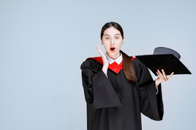 Portrait of beautiful woman in graduation outfit feeling surprised. High quality photo