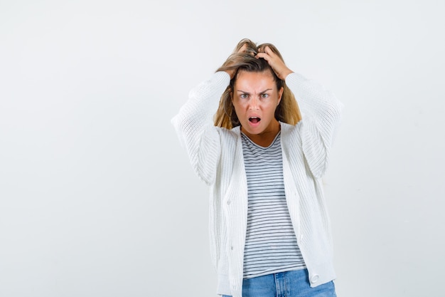 Portrait of beautiful woman holding hair with hands in jacket and looking excited front view