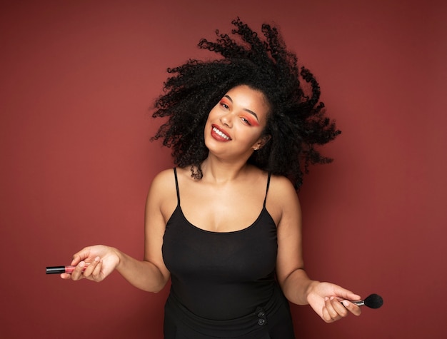 Free photo portrait of a beautiful woman holding lipstick and make-up brush