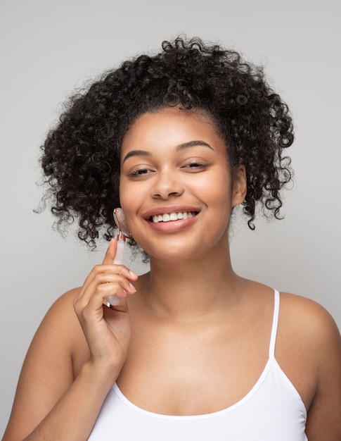 Portrait of a beautiful woman massaging her face with a massage roller