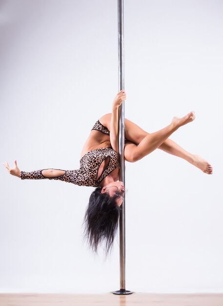 Portrait of a beautiful woman pole dancing on isolated white background