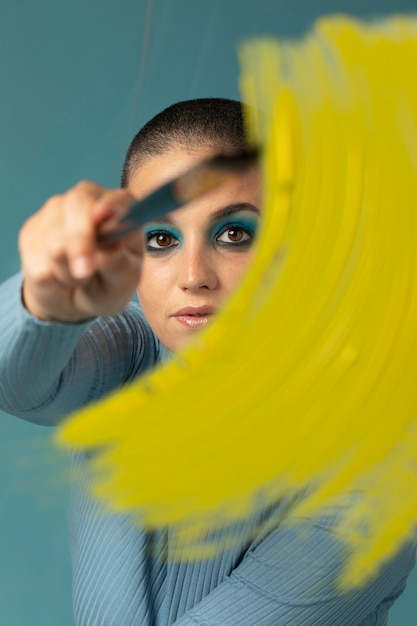 Portrait of beautiful woman posing in a turtleneck with yellow paint brush stroke