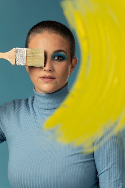 Free photo portrait of beautiful woman posing in a turtleneck with yellow paint brush stroke