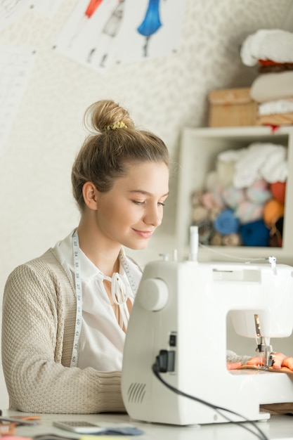 Free Photo portrait of a beautiful woman at sewing machine