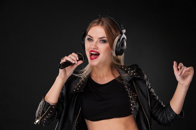 Portrait of a beautiful woman singing into microphone with headphones