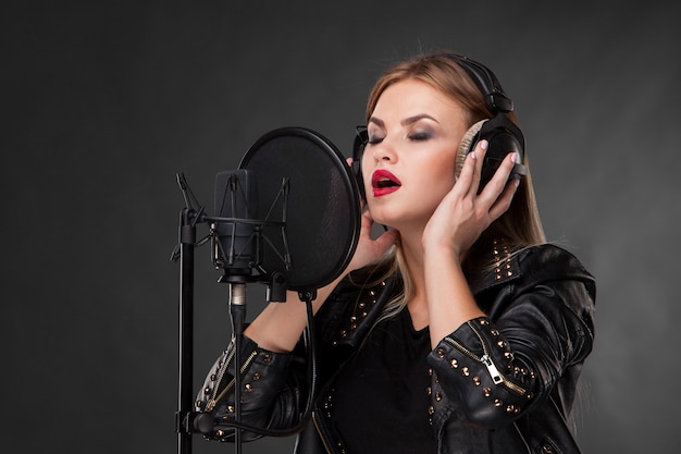 Portrait of a beautiful woman singing into microphone with headphones